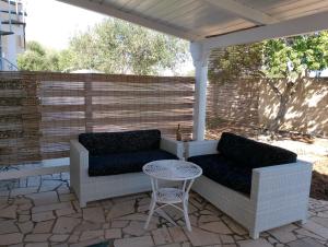 a patio with two couches and a table and a fence at Finestre Sul Mare Salento - Case Vacanze in Punta Prosciutto