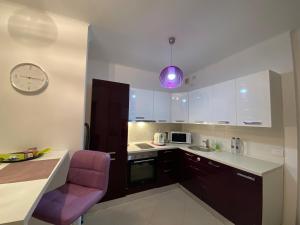 een keuken met een paarse stoel en een klok aan de muur bij Central Apartment in Timişoara