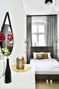 a white bedroom with a bed and a mirror at Angel Apartment Taczaka in Poznań