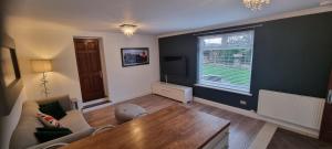 a living room with a couch and a table and a window at Laighdykes Guest Cottage in Saltcoats