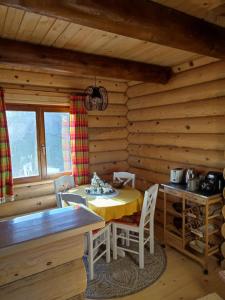 a dining room with a table and chairs in a cabin at Brvnara Pahuljica Zlatar in Nova Varoš