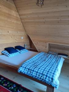 a bed in a room with a wooden wall at Brvnara Pahuljica Zlatar in Nova Varoš