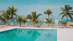 a swimming pool next to a beach with palm trees at Makáry Beach Tolú by Bernalo Hotels in Tolú +19 photos