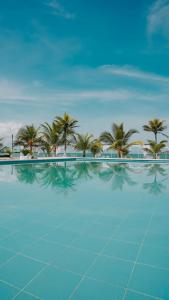a large swimming pool with palm trees in the background at Makáry Beach Tolú by Bernalo Hotels in Tolú