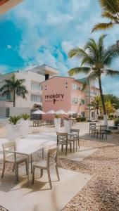 MAKARY BEACH HOTEL في تولو: مجموعة طاولات وكراسي أمام المبنى