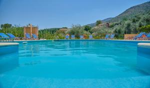 a large swimming pool with chairs and mountains in the background at Nikos Kalamaki Corfu in Apraos