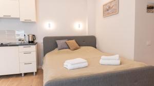 a bedroom with a bed with towels on it at Apartamentai Gastrolės in Palanga