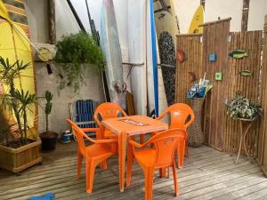 Barrinha dos Ventos في ساو لورينسو دو سول: طاولة برتقالية وكراسي على سطح مع ألواح ركوب الأمواج