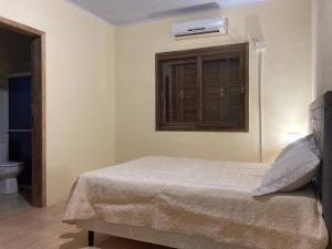 南聖洛倫索的住宿－Barrinha dos Ventos，一间卧室设有一张床、一个窗口和一个卫生间