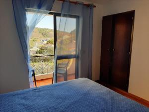 a bedroom with a bed and a window with a view at Casa dos Pais in Odeceixe
