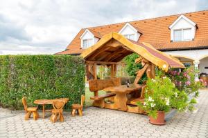 a wooden gazebo with a table and a table and chairs at Appartementhaus Martina in Mörbisch am See