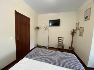 a bedroom with a bed and a television and a door at THE RIVER HOUSE - Termas Guesthouse in Termas de Sao Pedro do Sul