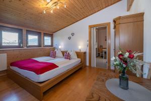 a bedroom with a bed and a vase of flowers on a table at Gästehaus Nassfeld in Tröpolach