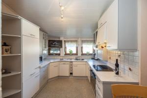 a large kitchen with white cabinets and a sink at Gästehaus Nassfeld in Tröpolach