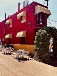un edificio rojo con mesas y sillas delante de él en Hostal Casa López en La Zarza