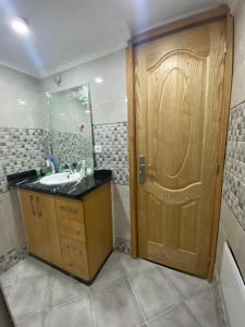 ein Badezimmer mit einer Holztür und einem Waschbecken in der Unterkunft Ayah's Vacation Home in Sidi Yahia az Zaʼer