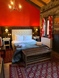 1 dormitorio con 1 cama grande y pared roja en Chalet Asteras tou Vorra, en Palaios Agios Athanasios