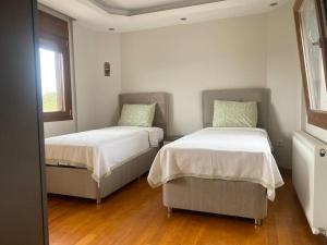 two beds in a room with two windows at Nefes URLA Villa Sea View. in Urla