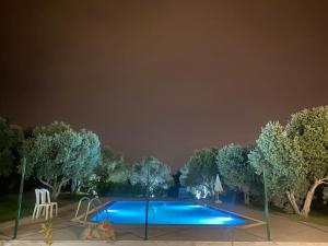 a swimming pool lit up at night with trees around it at Nefes URLA Villa Sea View. in Urla