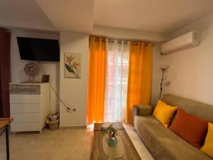 a living room with a couch and a window with orange curtains at Estudios Costavigía Mazagón by Ramona in Mazagón
