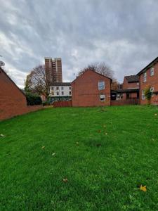 een grasveld met gebouwen op de achtergrond bij 2 Bedroom Cozy Chambers with free parking in Leeds