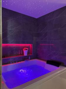 ein lila Badezimmer mit einer Badewanne mit rosafarbener Beleuchtung in der Unterkunft Loving room cocooning avec jacuzzi « la terre » in Jujurieux