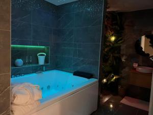 eine blaue Badewanne im Bad mit einer gefliesten Wand in der Unterkunft Loving room cocooning avec jacuzzi « la terre » in Jujurieux