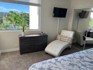 um quarto com uma cama, uma cadeira e uma janela em Stunning Views Best location in Hilo 2BR modern Condo em Hilo