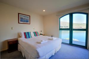 a bedroom with a large bed and a large window at Frankton House - Queenstown Holiday Home in Queenstown