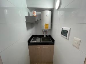 una pequeña cocina con fregadero y calentador de agua en TinyApartments - estudio pleno centro Concepción en Concepción