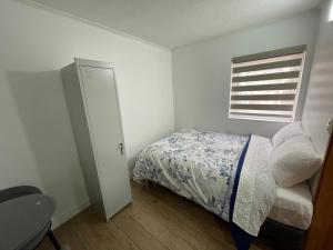 Habitación pequeña con cama y ventana en TinyApartments - estudio pleno centro Concepción en Concepción