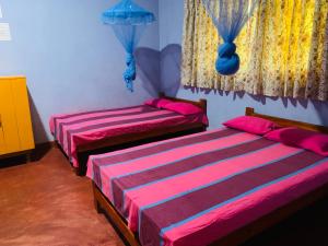 two beds in a room with pink and purple sheets at Coco Garden Holiday Homes in Anuradhapura