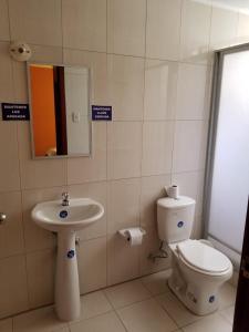 a bathroom with a toilet and a sink and a mirror at HOSTAL EL CONFORT QUITO NORTE in Quito