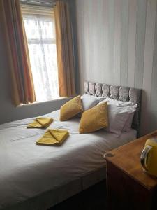 een bed met 2 gele kussens en een raam bij JEANNE in Blackpool