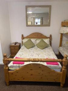 een houten bed in een slaapkamer met een spiegel bij JEANNE in Blackpool