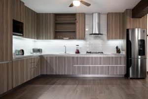 uma cozinha com armários de madeira e um frigorífico de aço inoxidável em Espacioso, moderno con amenidades en Tulancingo 2 em Monterrey