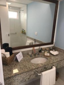 a bathroom counter with a sink and a large mirror at Hotel Búzios Resort com Entretenimento in Búzios