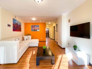 a living room with a white couch and a tv at Casa Abaroa in La Paz