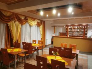 a restaurant with wooden tables and chairs and yellow drapes at Penzion Zornicka in Bardejovské Kúpele