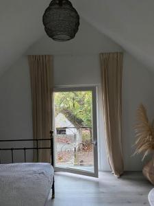 a bedroom with a door open to a balcony at Hofstede klein Rozendaal, huisje Rozen in Asch