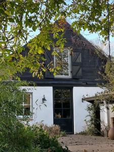 a black and white house with a window and a door at Hofstede klein Rozendaal, huisje Rozen in Asch