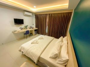 a bedroom with a bed and a desk and a monitor at Tall Tree Kata Phuket in Kata Beach