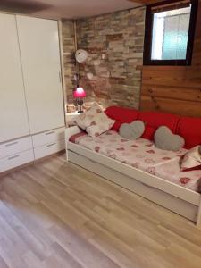 a bedroom with a red couch and a brick wall at at foot of Mont Blanc studio 2 p in Cluses
