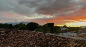 um pôr-do-sol sobre um telhado com uma montanha ao fundo em Encuentros em Granada