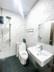 a white bathroom with a toilet and a sink at Tall Tree Kata Phuket in Kata Beach