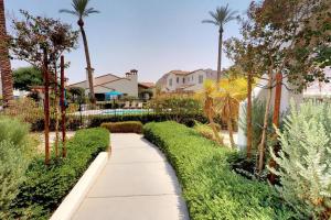 a walkway through a garden with palm trees at LV305 Legacy Villas Townhome w Expansive Patio in La Quinta