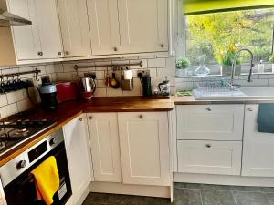 cocina con armarios blancos, fregadero y ventana en Lovely 2 bed Hampstead Apartment en Londres