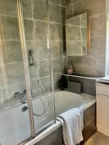 a bathroom with a tub and a shower with a mirror at Lovely 2 bed Hampstead Apartment in London
