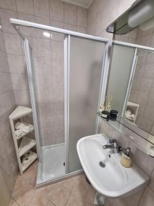 a white bathroom with a shower and a sink at Little cozy apt close to centre in Ljubljana