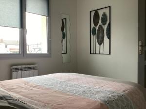 1 cama en un dormitorio con 2 ventanas en Joli appartement 50 m2 classé 3 etoiles avec terrasse et jardin, en La Rochelle